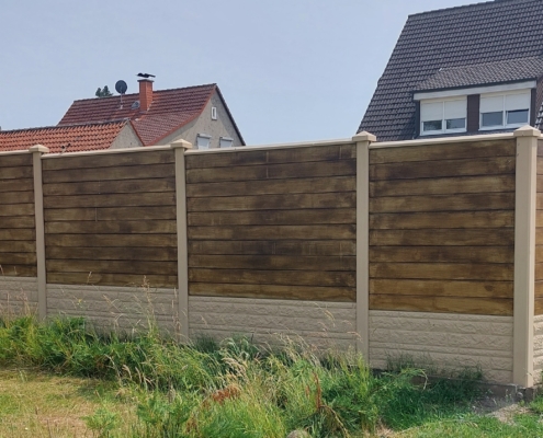 Betonzaun Kombination von zwei Motiven: Glatt mit Nut und Fels. Fels ist im Sand und Glatt mit Nut ist in Holzoptik