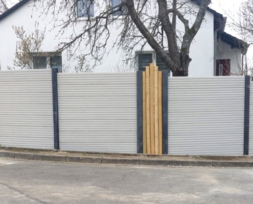 Betonzaun Motiv Kopenhagen in grau-weiß, zwischen Zaunelementen ist ein Element aus Bambus
